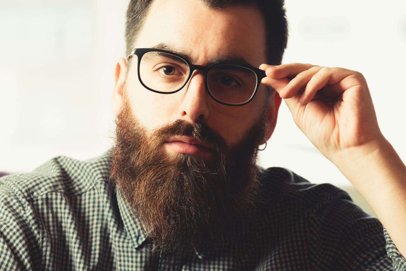 A bearded man adjusting black acetate glasses