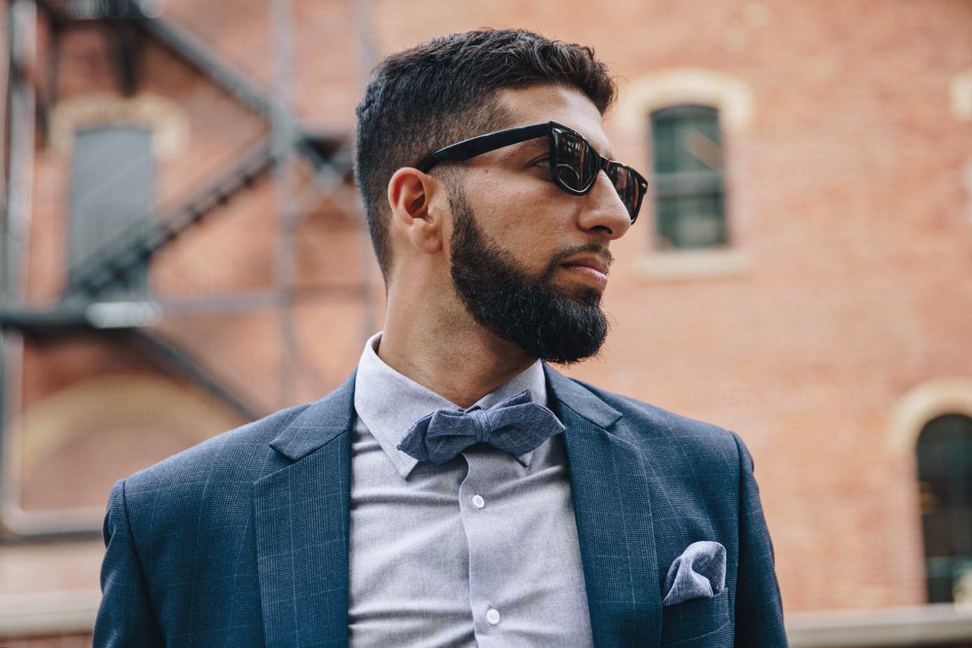 A bearded man in a suit wearing sunglasses