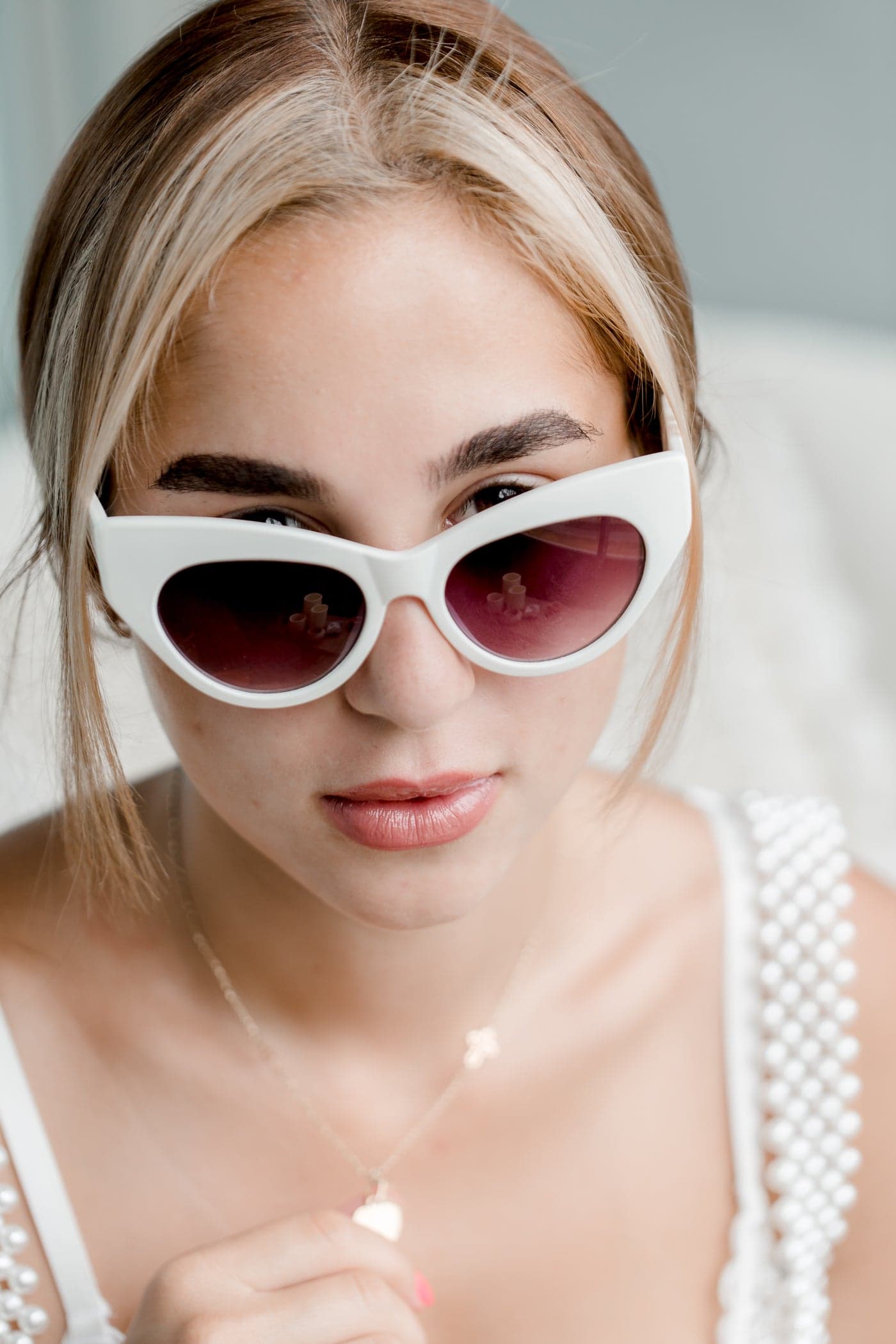 A woman wearing white cat-eye sunglasses